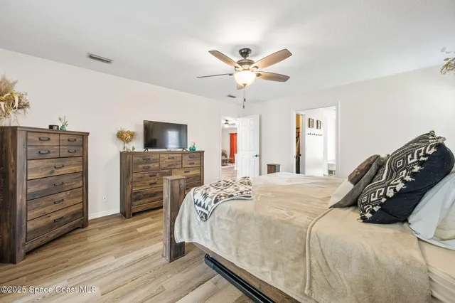 a bedroom with a bed a dresser and a flat screen tv