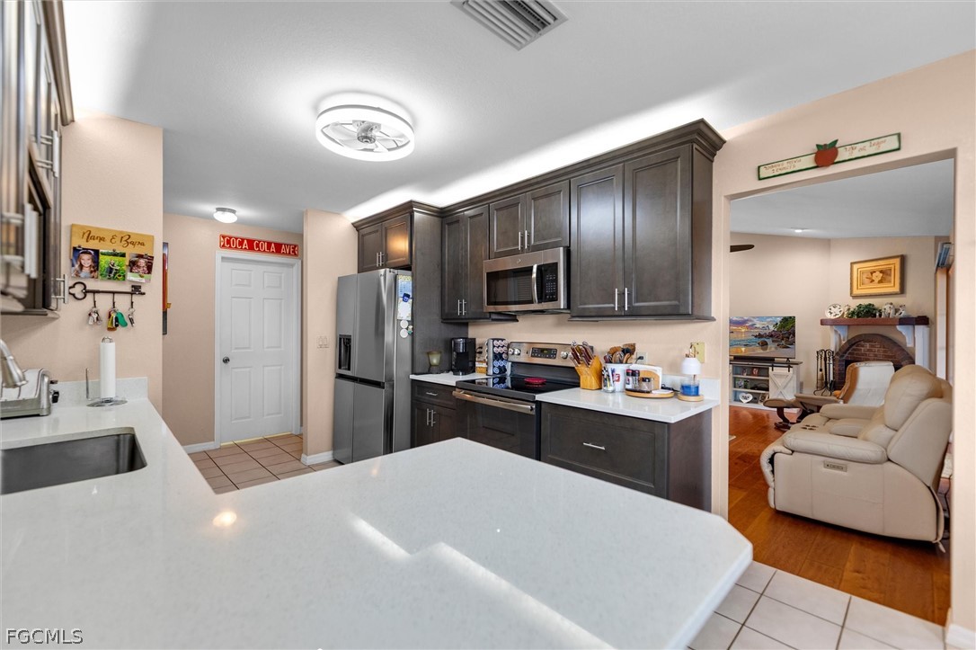 5997 Dragoon Court Fort Denaud, FL 33935 - Photo 19 of 49 a kitchen with a refrigerator a stove top oven a sink dishwasher and white cabinets with wooden floor