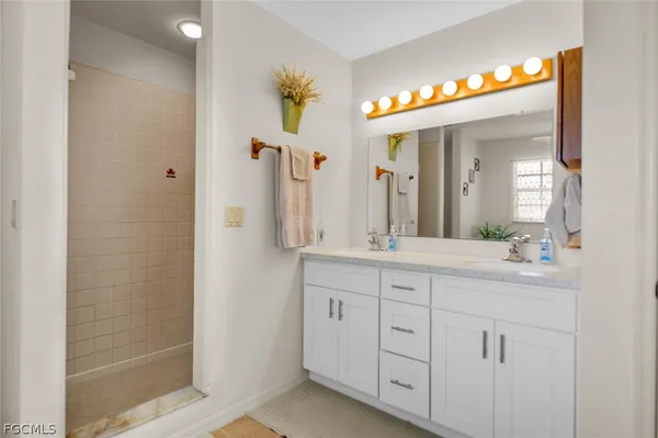 a spacious bathroom with a granite countertop sink a mirror and a shower