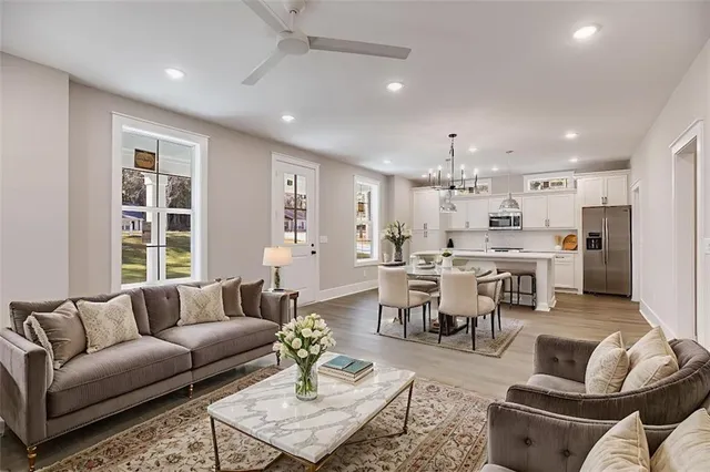 a large white kitchen with kitchen island a sink wooden floor and a refrigerator