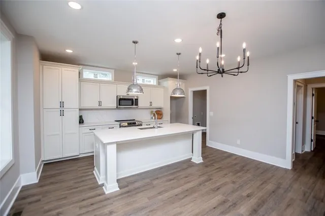 a kitchen with stainless steel appliances a refrigerator a sink dishwasher a stove and white cabinets with wooden floor