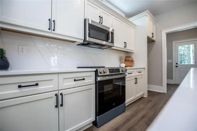 a kitchen with stainless steel appliances white cabinets and a stove top oven