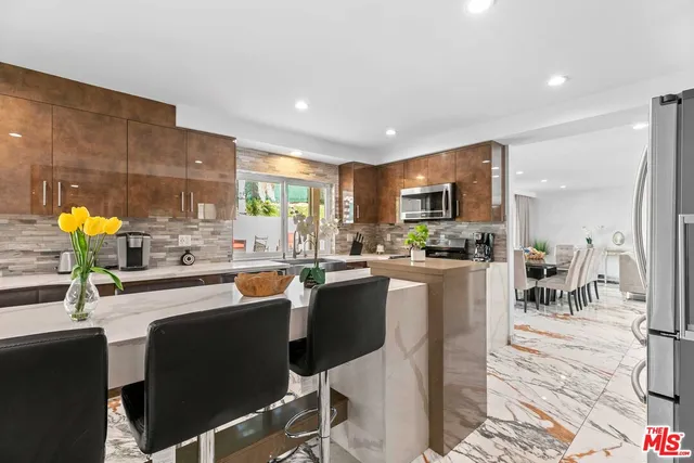 a kitchen with stainless steel appliances kitchen island granite countertop a refrigerator and cabinets