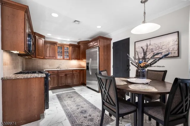 a kitchen with stainless steel appliances granite countertop a table chairs and a refrigerator