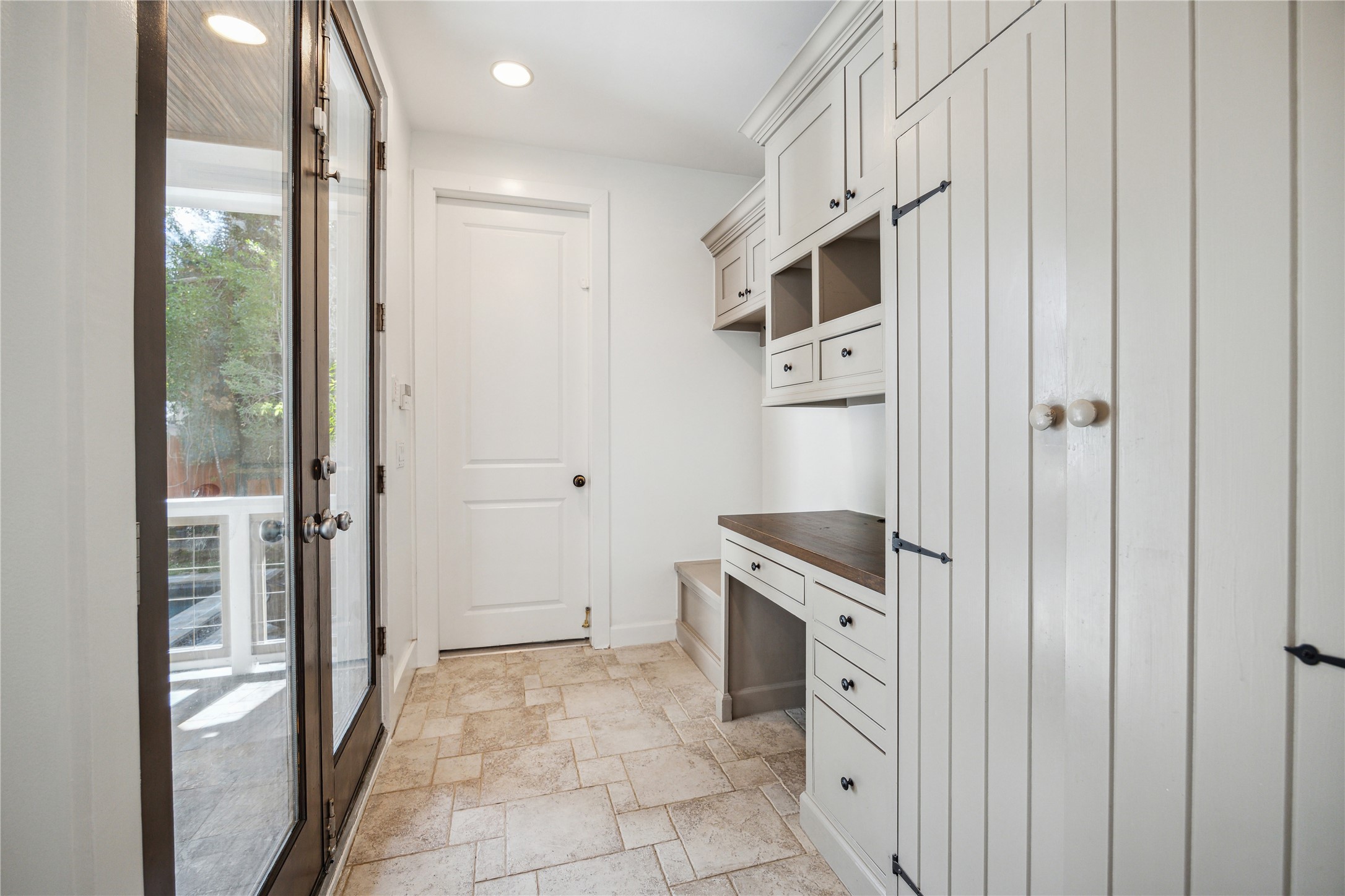 1238 West 22nd Street Houston, TX 77008 - Photo 13 of 43 Mudroom (10x6) with desk, storage bench, tile flooring, and cabinetry. It leads to a large 2-car garage with high ceilings and bike pulleys and to the covered patio