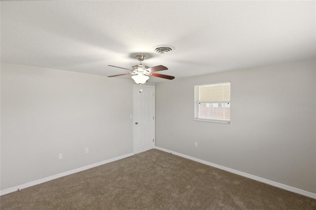 1107 Seneca Road Venice, FL 34293 - Photo 14 of 30 an empty room with a chandelier fan and windows