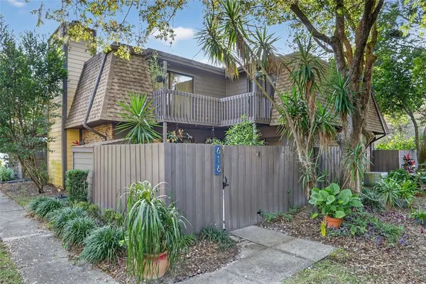 a front view of small house with plants and trees