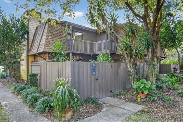 a front view of small house with plants and trees