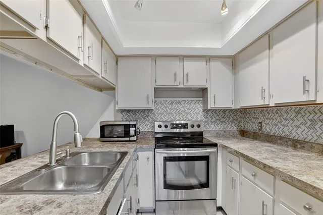 a kitchen with granite countertop a sink a stove and cabinets