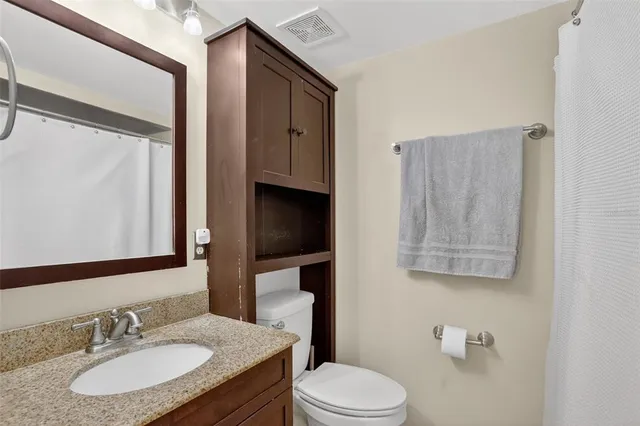 a bathroom with a granite countertop toilet sink and mirror
