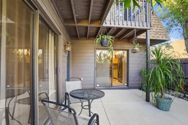 a view of a backyard with table and chairs potted plants and floor to ceiling window