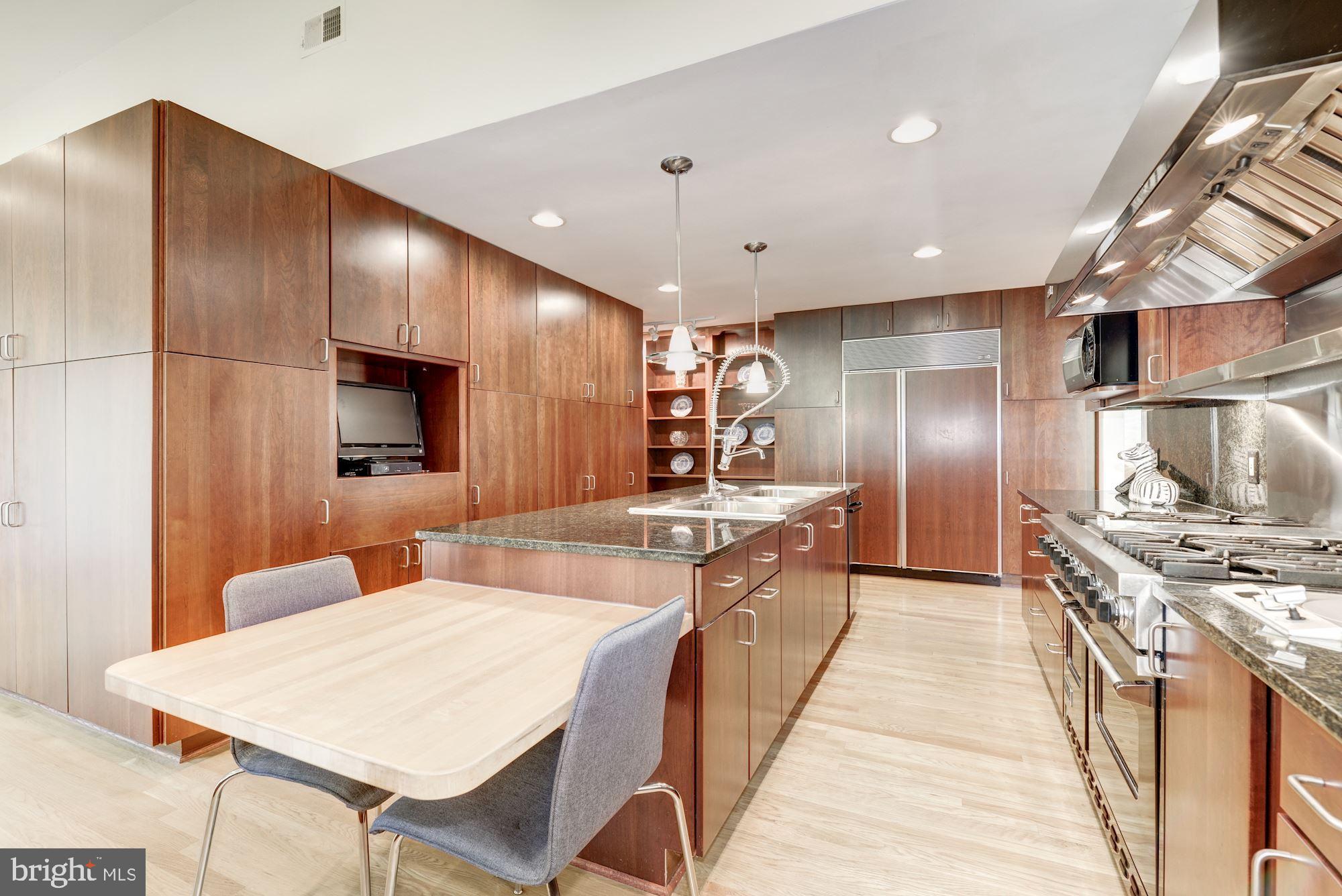 6129 Overlea Road Bethesda, MD 20816 - Photo 19 of 30 a large kitchen with stainless steel appliances kitchen island granite countertop a large kitchen island a stove a refrigerator with a dining table and chairs