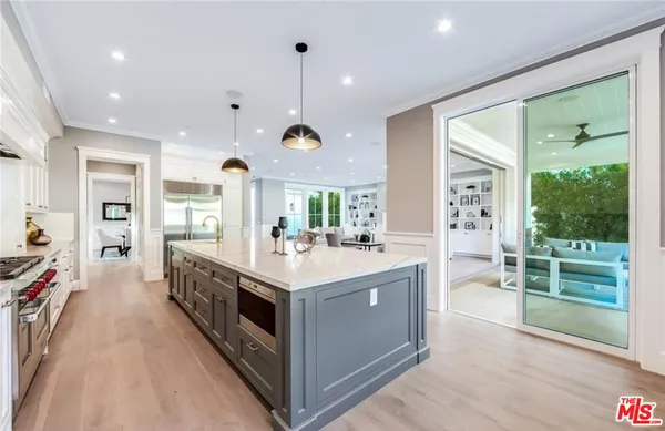 a large kitchen with stainless steel appliances a large counter top a stove and a wooden floors