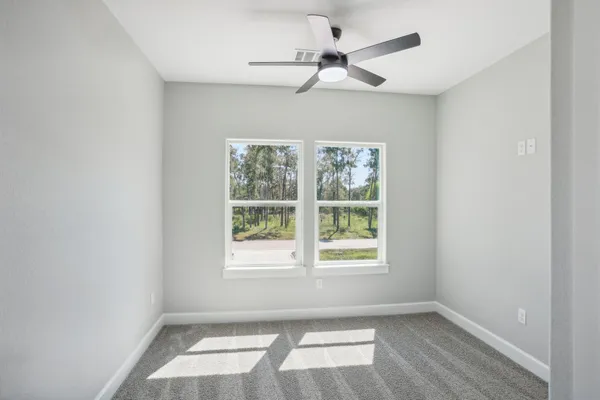 an empty room with a window and a fan