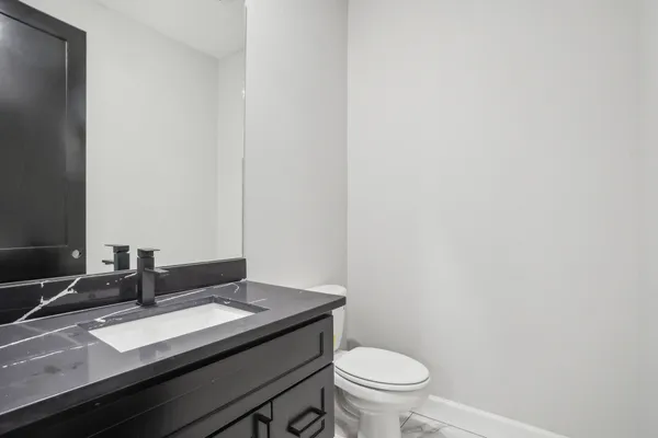 a bathroom with a granite countertop sink toilet and mirror