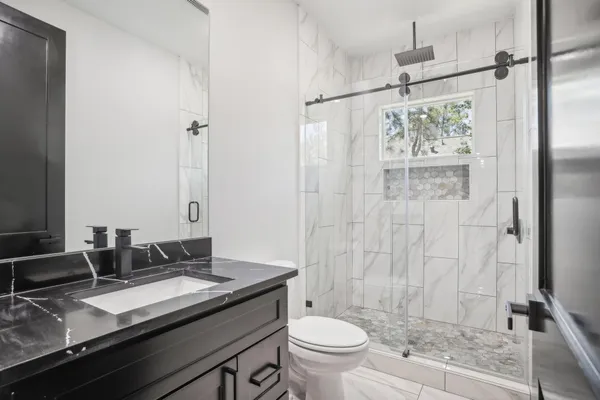 a bathroom with a granite countertop sink toilet and shower