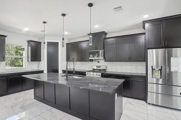a kitchen with kitchen island granite countertop a sink refrigerator and microwave