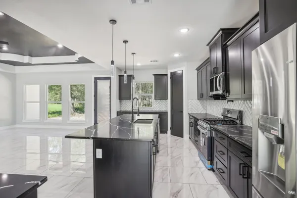 a large kitchen with stainless steel appliances kitchen island granite countertop a stove refrigerator and cabinets