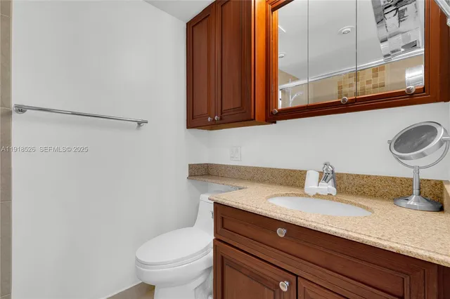 a bathroom with a granite countertop sink a toilet and mirror