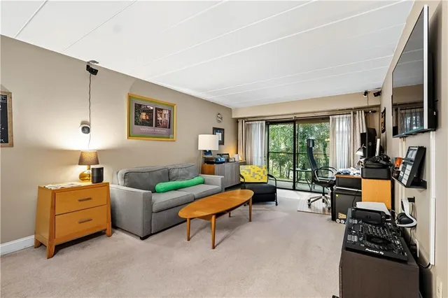 a living room with furniture a flat screen tv and a window