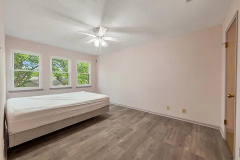 an empty room with wooden floor and ceiling fan
