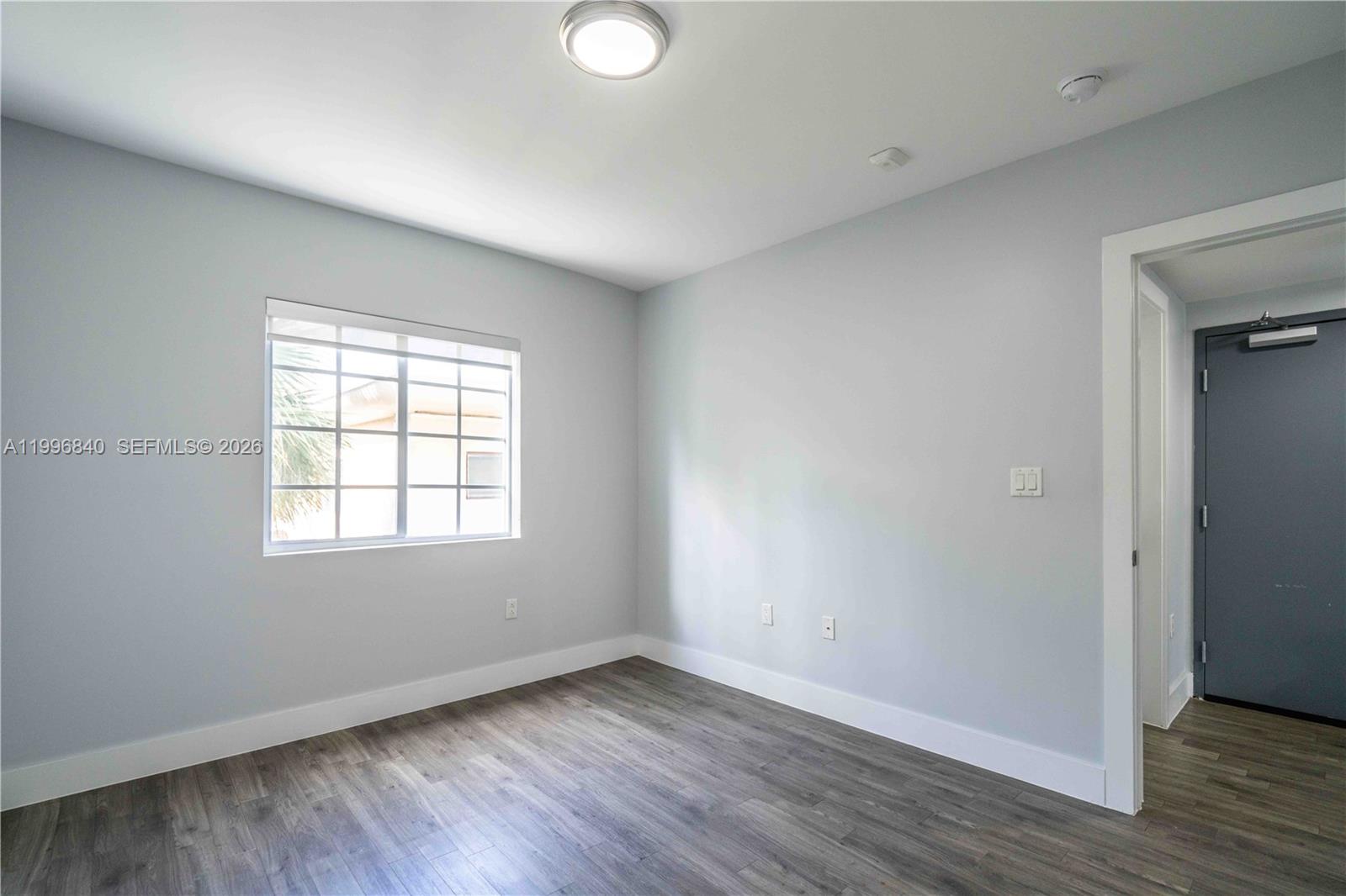 331 85th Street, Unit 17 Miami Beach, FL 33141 - Photo 11 of 16 an empty room with wooden floor and windows