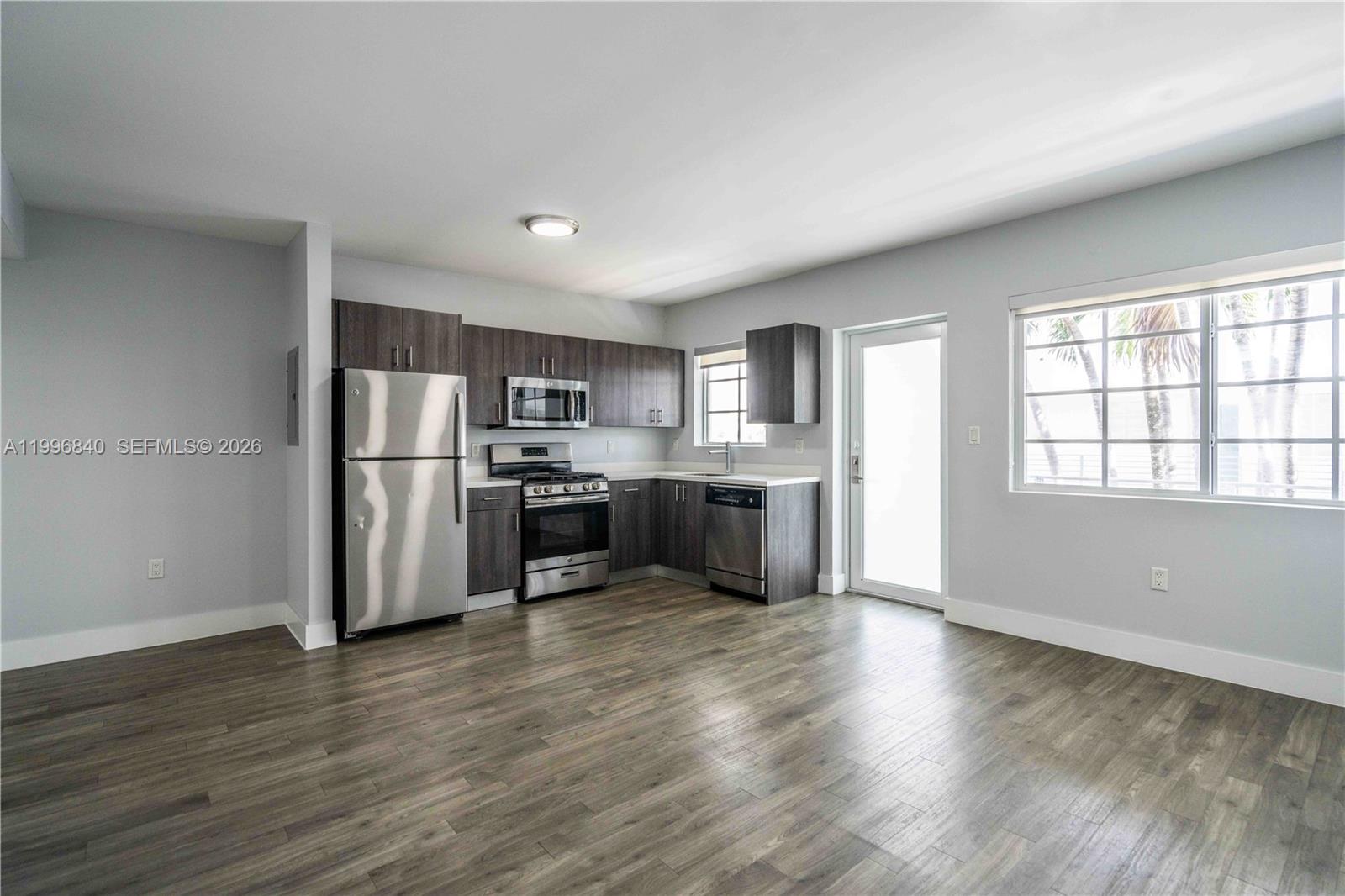 331 85th Street, Unit 17 Miami Beach, FL 33141 - Photo 3 of 16 a kitchen with stainless steel appliances granite countertop a refrigerator a sink dishwasher a stove with wooden floors and cabinets