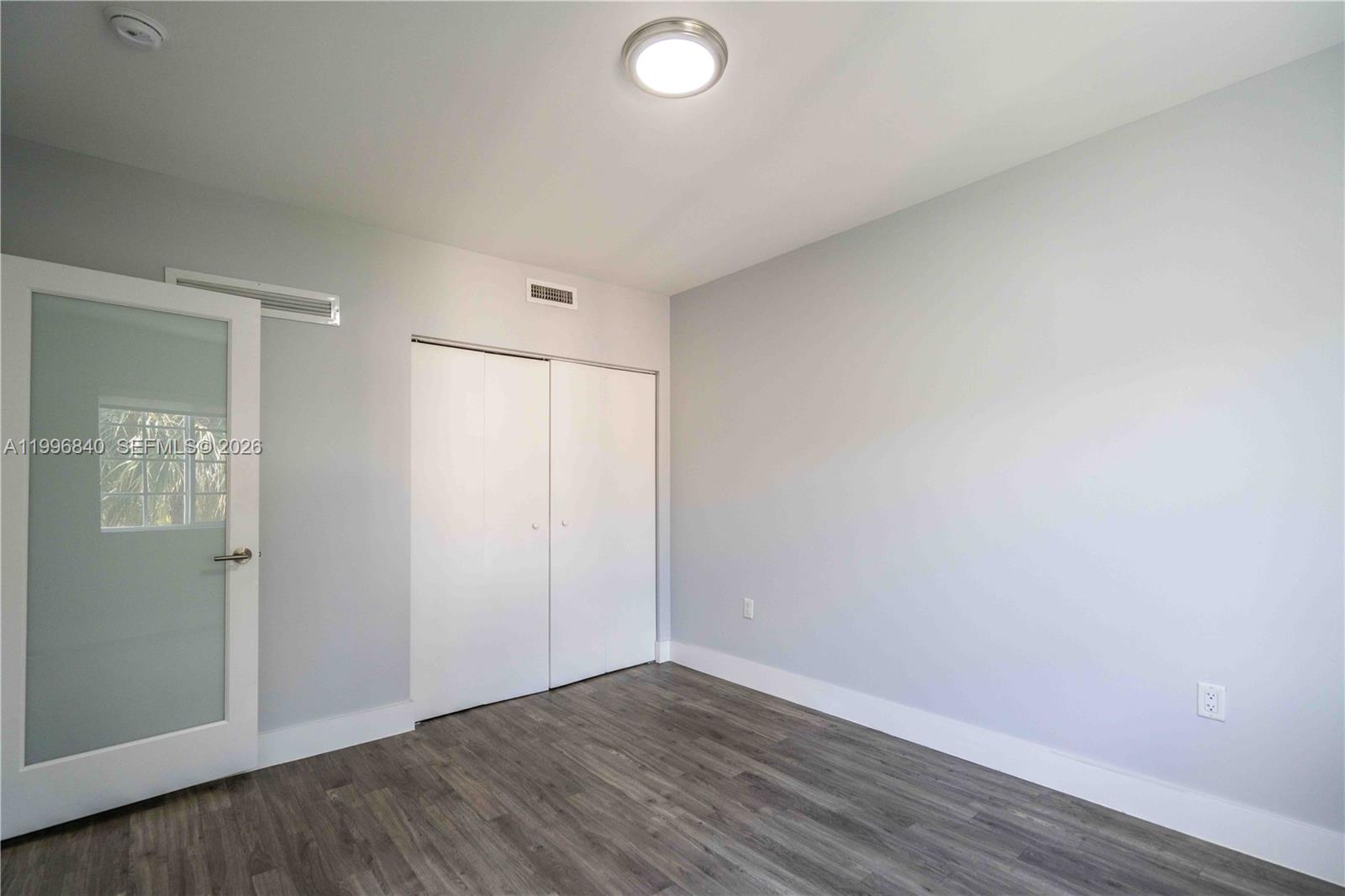 331 85th Street, Unit 17 Miami Beach, FL 33141 - Photo 9 of 16 an empty room with wooden floor and windows
