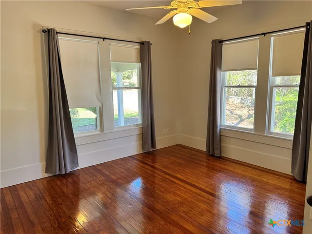 a view of an empty room with window and wooden floor