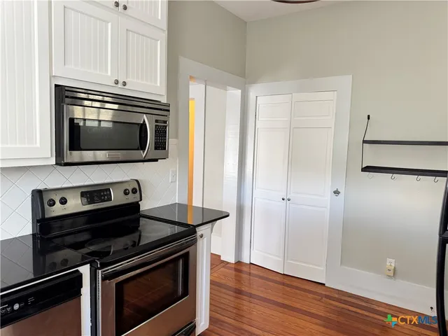a kitchen with granite countertop a stove and a microwave with wooden floor