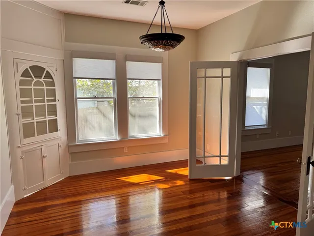 a view of an empty room with wooden floor and a window