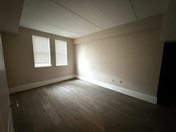an empty room with wooden floor and windows