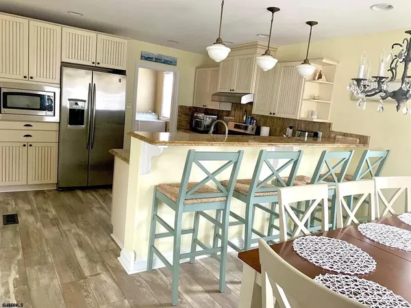 a kitchen with stainless steel appliances granite countertop a stove a sink dishwasher a refrigerator oven a dining table and chairs with wooden floor