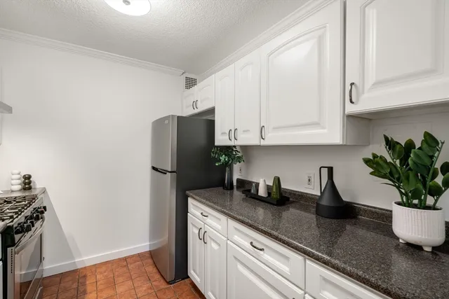 a kitchen with stainless steel appliances granite countertop a refrigerator a sink a stove and white cabinets