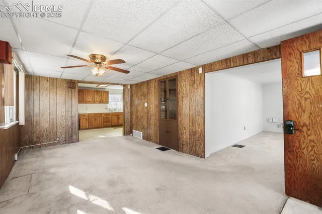 a view of a livingroom with a chandelier fan and windows