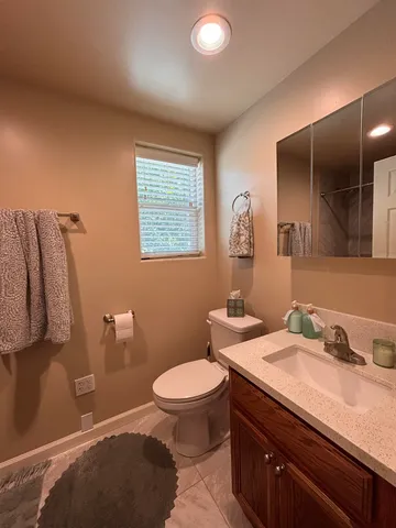 a bathroom with a granite countertop toilet sink and mirror