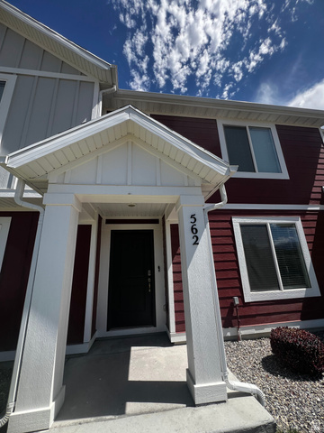 562 Hal Street, Unit 152 Tooele, UT 84074 - Photo 2 of 44 Welcoming portico entry with prominent house numbers, dark-paneled front door, and a contrasting crimson siding facade