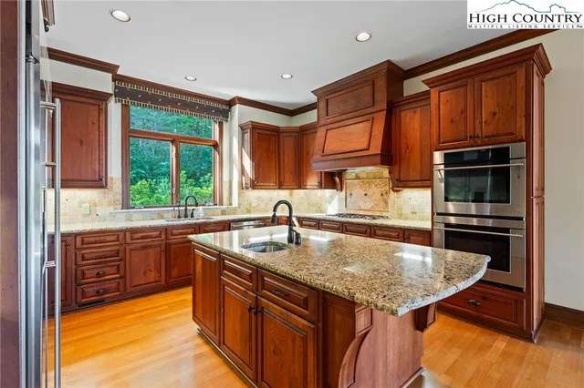 a kitchen with stainless steel appliances granite countertop a sink a stove and a refrigerator