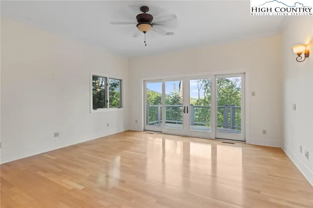 a view of an empty room with a window and wooden floor