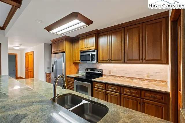 a kitchen with stainless steel appliances granite countertop a sink stove and refrigerator