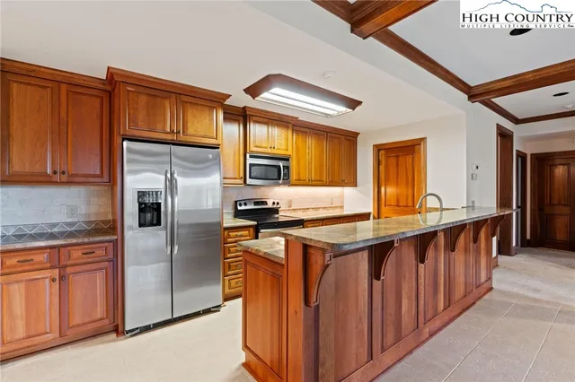 a kitchen with stainless steel appliances granite countertop a stove a refrigerator and a sink with wooden cabinets