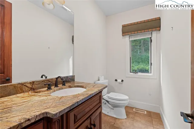 a bathroom with a granite countertop sink a toilet and a mirror