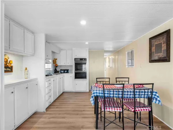 a kitchen with stainless steel appliances kitchen island granite countertop a refrigerator a sink dishwasher a dining table and chairs with wooden floor