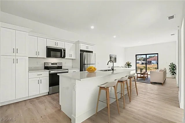 a kitchen with stainless steel appliances a stove a sink a refrigerator a dining table and chairs