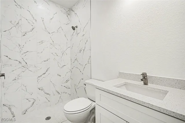 a bathroom with a granite countertop toilet sink and mirror