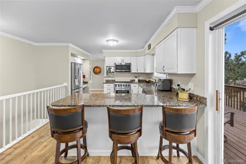 a kitchen with stainless steel appliances granite countertop a table chairs sink and cabinets