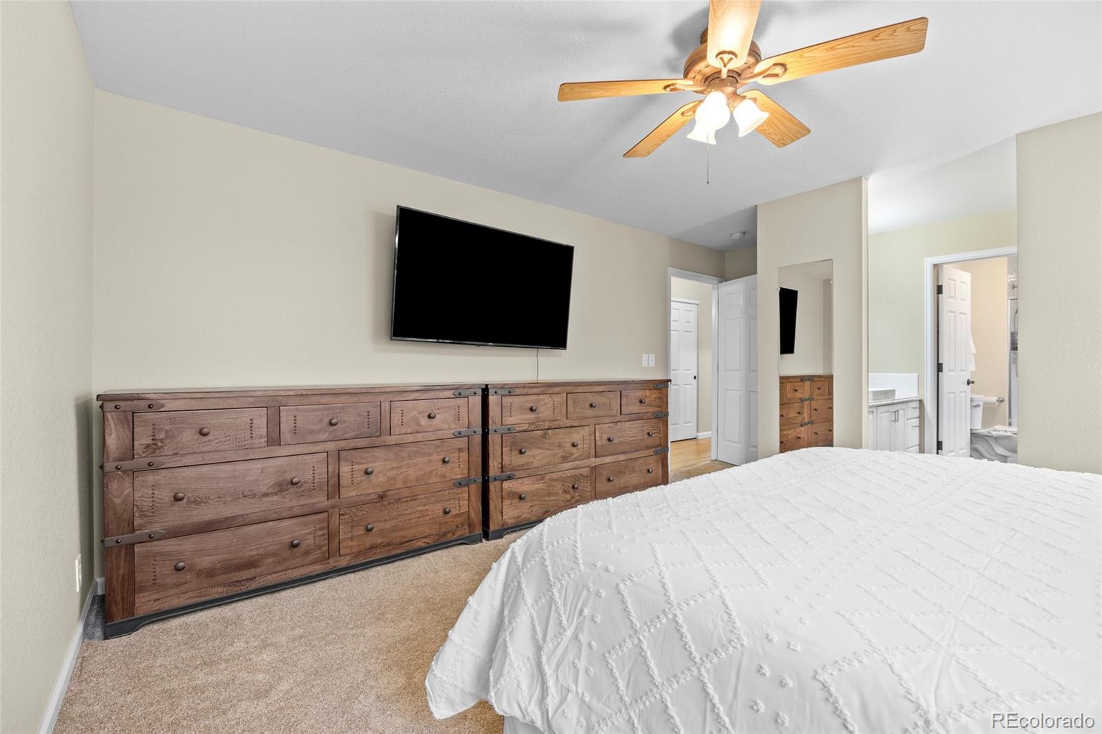 42865 Vista Ridge Road Parker, CO 80138 - Photo 20 of 50 a bedroom with a bed a flat screen tv and a chandelier