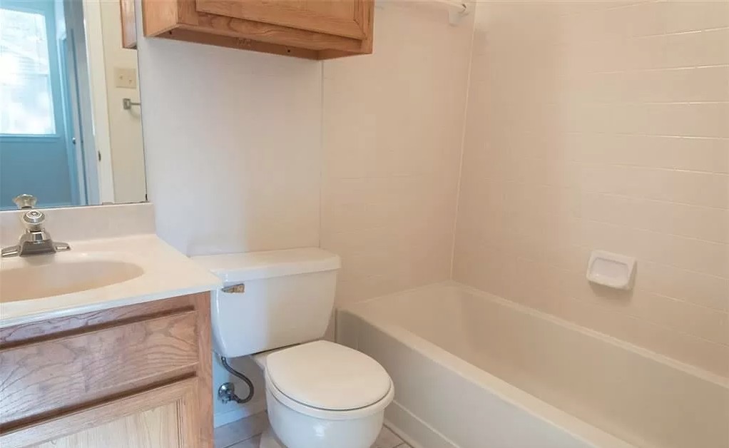 6501 Brush Country Road, Unit 102 Austin, TX 78749 - Photo 9 of 12 Tiled walls and classic wood cabinetry define this functional full bathroom.