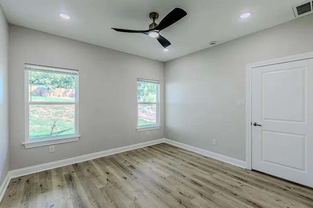 a view of empty room with wooden floor and fan