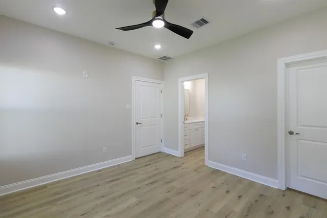 an empty room with wooden floor ceiling fan and window